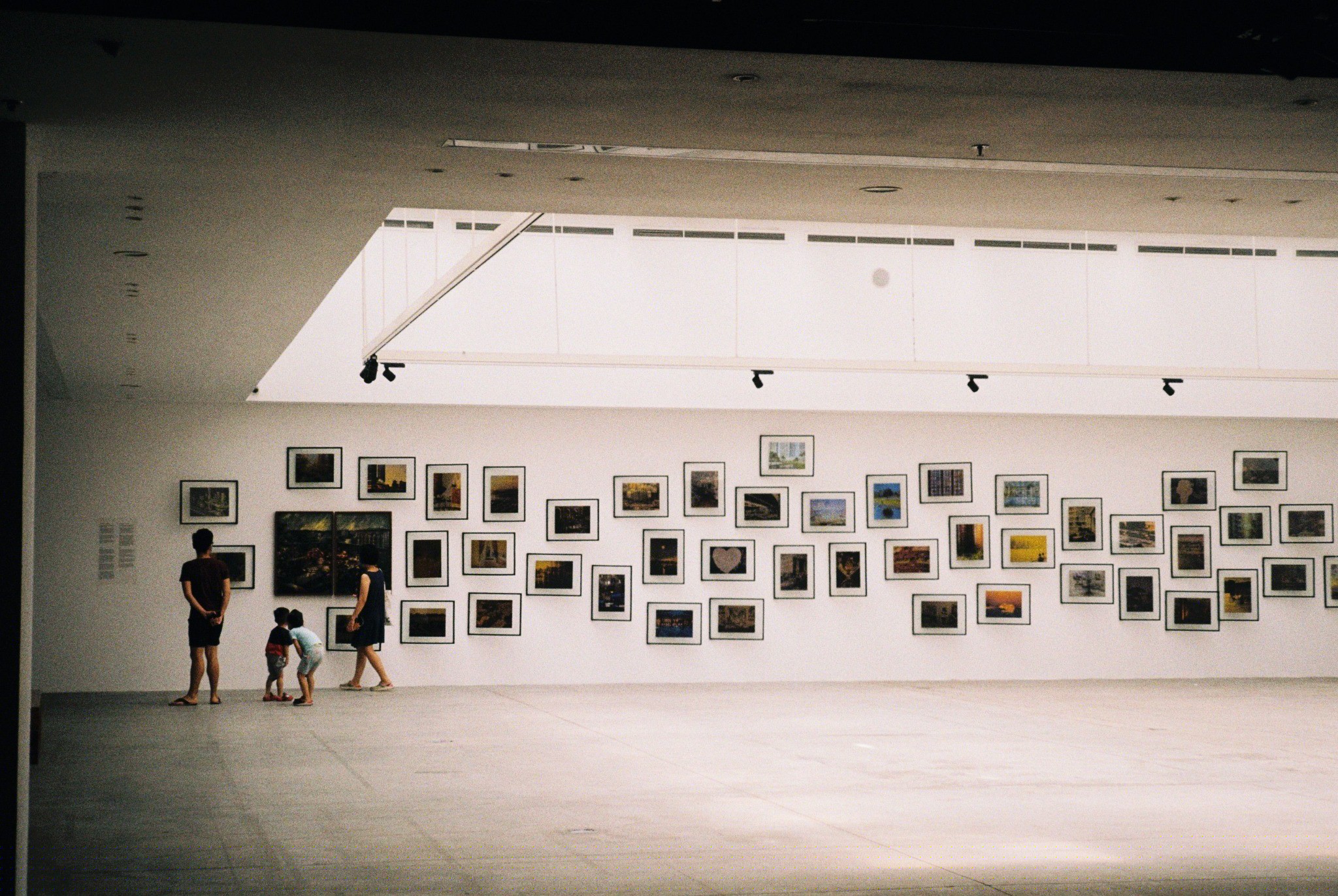 Group exhibition wall inside a spacious urban art gallery