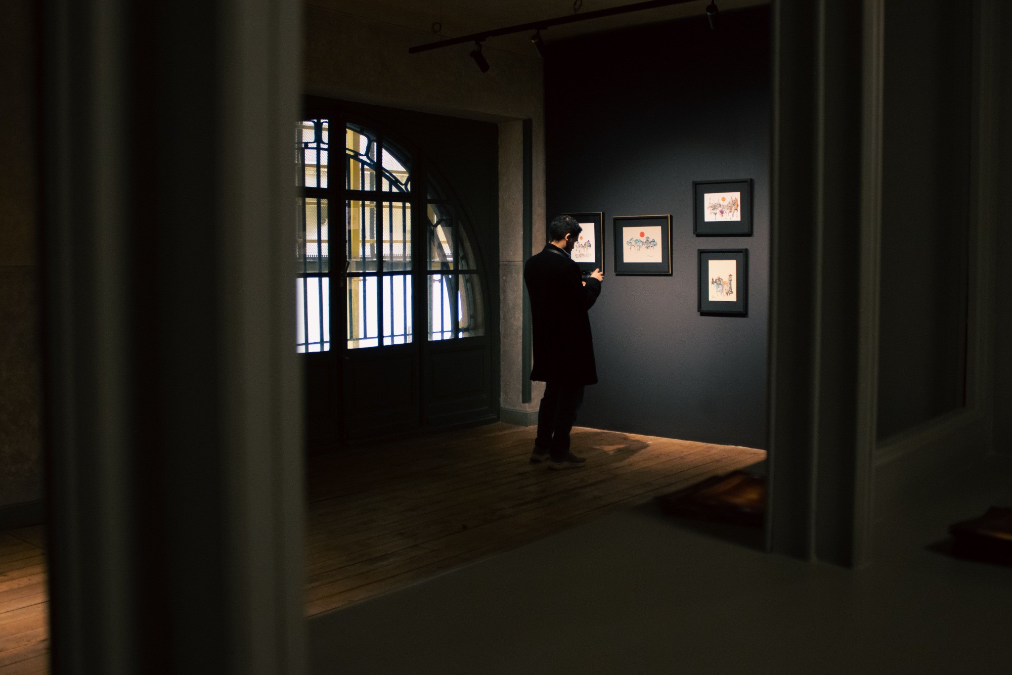 Visitor viewing framed works in an intimate urban art gallery