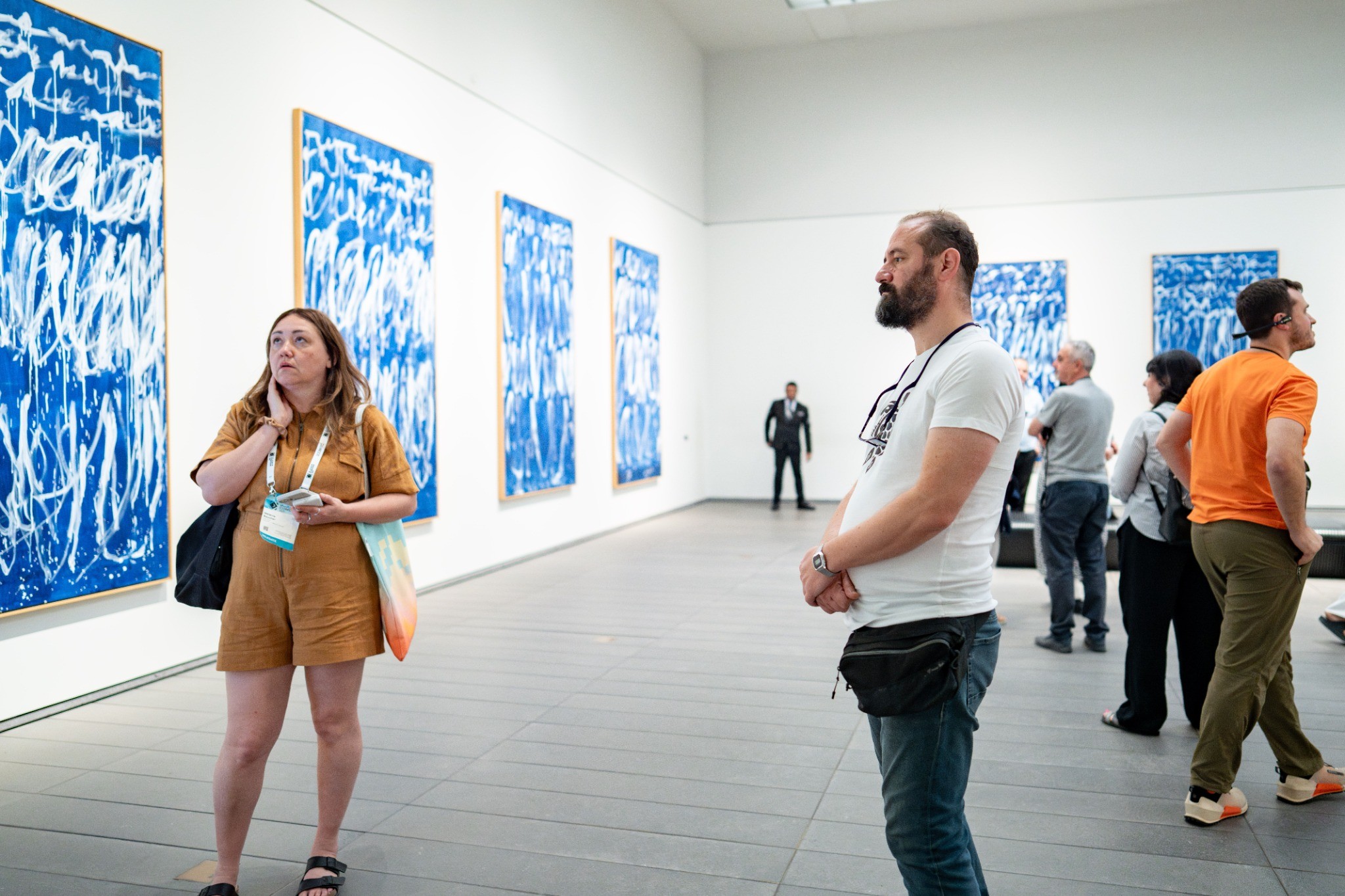 Visitors viewing blue contemporary artworks in an urban art gallery